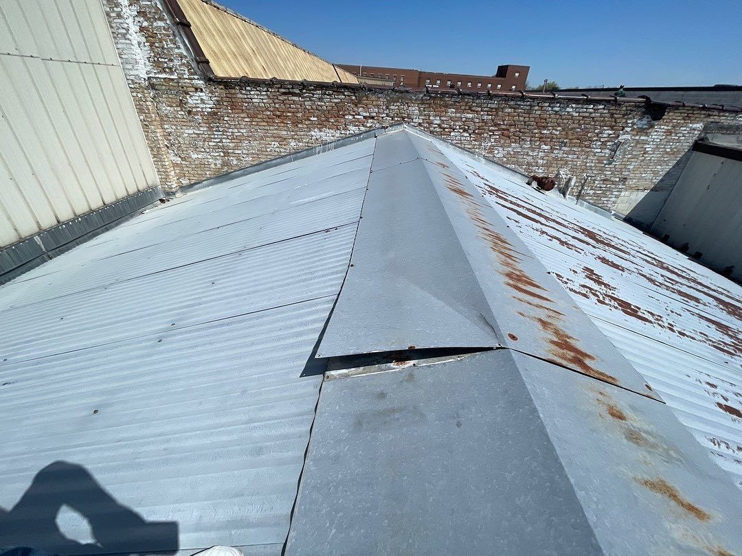 Wind-lifted ridge and panels on a metal roof.